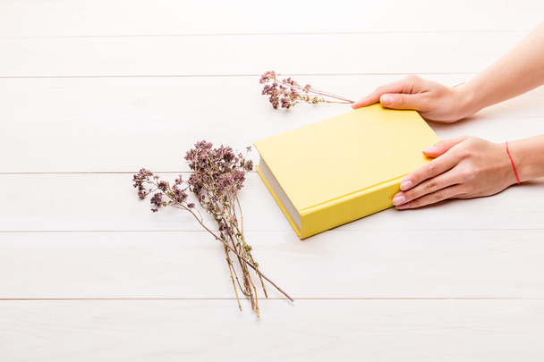 Female hands holding a closed yellow book - Fotoğraf, Görsel