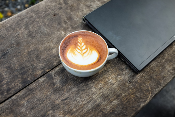 Latte art kahvikuppi kannettavat tietokone puupöydällä
 - Valokuva, kuva