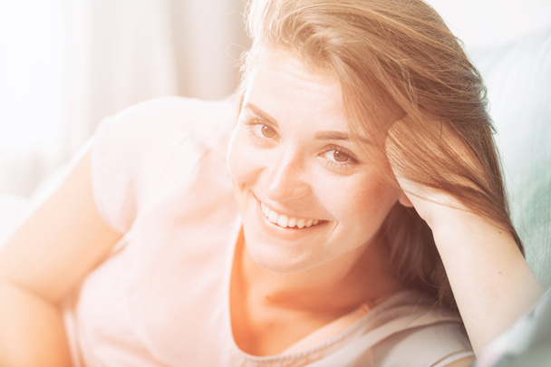 Szczęśliwa młoda kobieta, leżąc na kanapie w domu i uśmiecha się. Na co dzień chlew - Zdjęcie, obraz