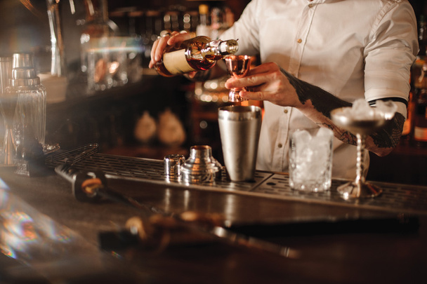 Bartender is adding ingredient in shaker at bar counter - 写真・画像