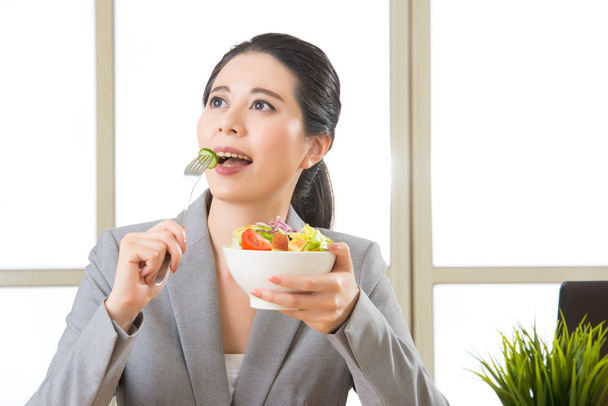 Joven mujer de negocios asiática disfrutando de una ensalada saludable
 - Foto, Imagen
