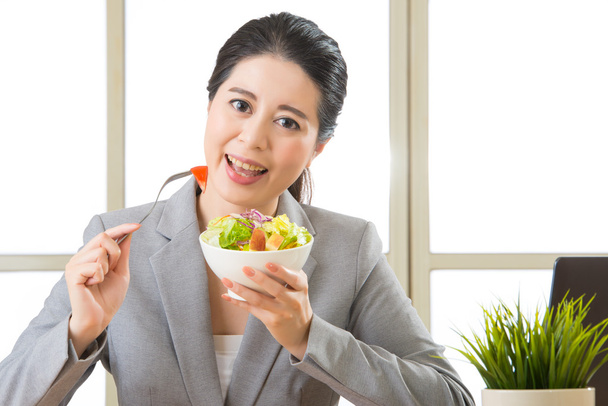 Молода азіатська бізнес-леді насолоджується здоровим салатом
 - Фото, зображення