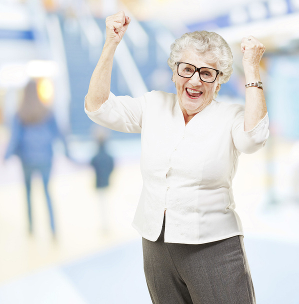 Portret van een gelukkig senior vrouw doen een gebaar van de overwinning op mall - Foto, afbeelding