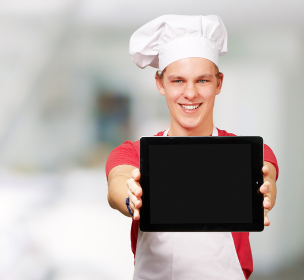 retrato del joven cocinero mostrando una tableta digital en el interior
 - Foto, Imagen