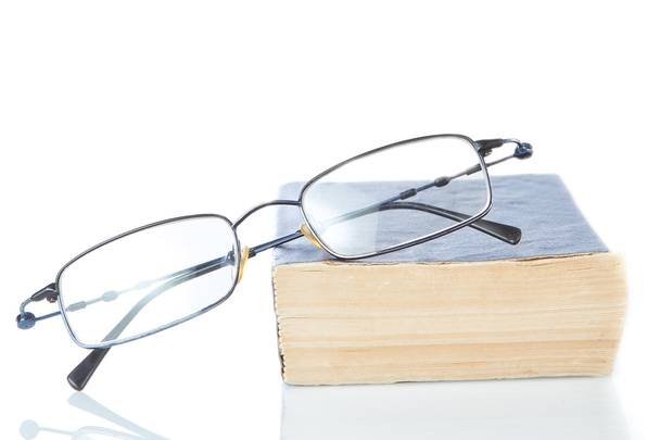 The book is a dictionary and glasses on a white background. - 写真・画像