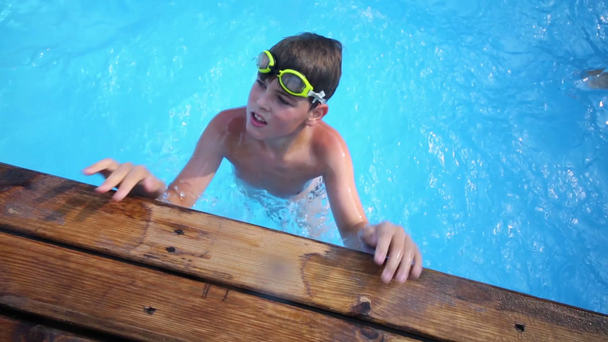 Boy in swimming goggles in outdoor pool - Footage, Video