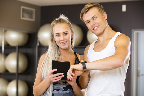 Uśmiechnięta młoda kobieta i mężczyzna z tabletu w siłowni fitness - Zdjęcie, obraz