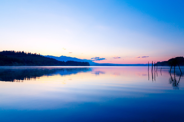 красивый пейзаж с горами и озером на рассвете в золотых, синих и фиолетовых тонах
. - Фото, изображение