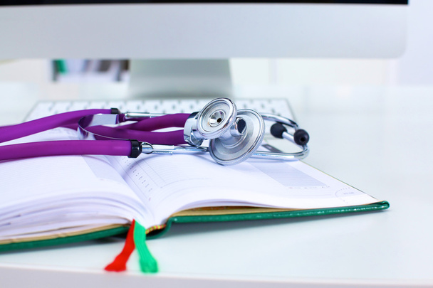 Stetoskop, ležící na stole na rozevřené knize - Fotografie, Obrázek