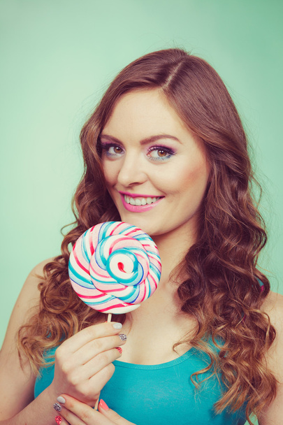 Smiling girl with lollipop candy on teal - Foto, afbeelding
