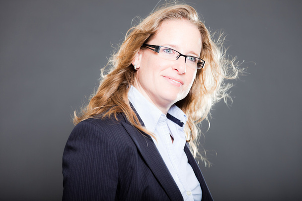 Pretty business woman long blond hair wearing glasses and blue suit. Isolated on grey background. Studio shot. - Photo, Image