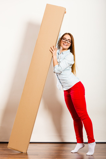Happy woman moving into apartment carrying box. - 写真・画像