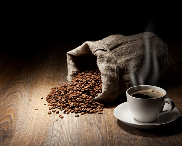 Kaffeetasse mit gerösteten Bohnen auf rustikalem Tisch - Foto, Bild