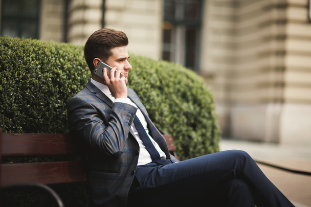 Stylish young businessman talking on the phone outdoors - Фото, изображение