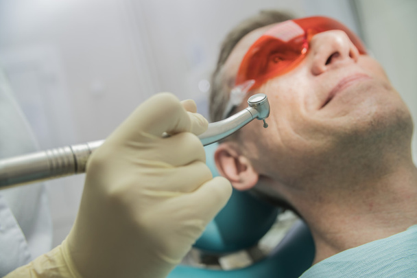クローズ アップ歯科医療コンセプト口腔検査。患者は、彼の前に歯科で椅子に手ドリル - 写真・画像