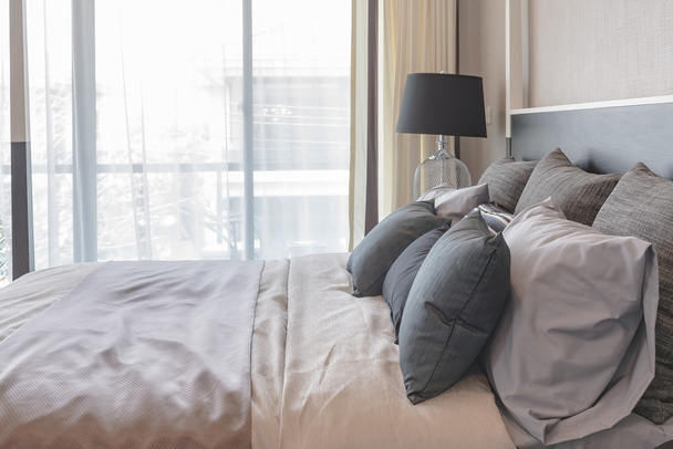 oreillers sur le lit et style lampe noire de luxe sur le côté de la table en bois
  - Photo, image