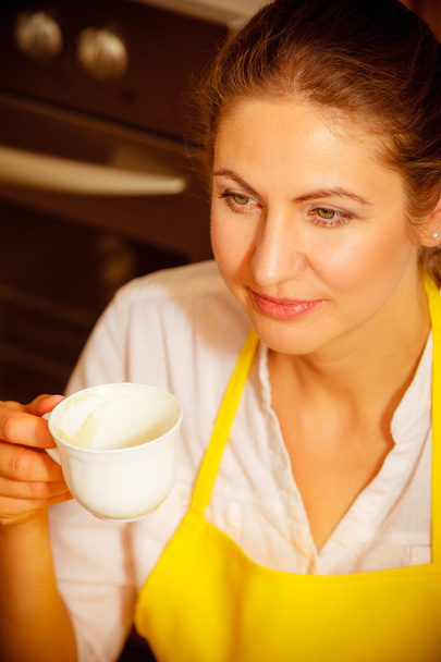Zralá žena držící šálek kávy v kuchyni. - Fotografie, Obrázek