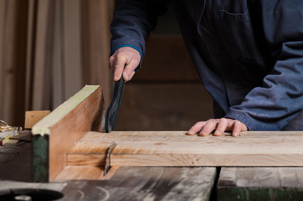 Mãos de carpinteiro que cortam a placa de madeira com serra de mesa
 - Foto, Imagem