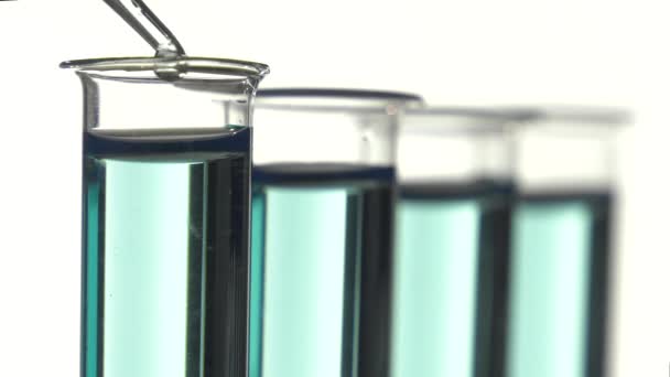Reagenzglas gefüllt mit bleu Flüssigkeit, gießt einen Tropfen Wasser - Filmmaterial, Video