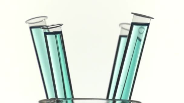 青色の液体はターン テーブル上で試験管をいっぱい - 映像、動画