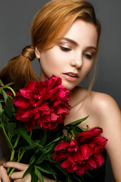 Beautiful girl with a bouquet of peonies. Model with a gentle make-up. Beauty face. - Photo, Image