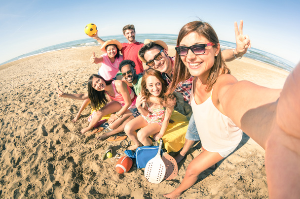 Groep van multiraciale gelukkig vrienden selfie te nemen en plezier maken met sport spelletjes op het strand - zomer vreugde concept en multi etnische vriendschap - zonnige middag kleur tinten met focus op meisje houdt van de camera - Foto, afbeelding