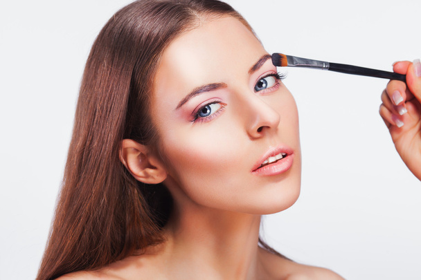 Beautiful woman applying pink eye makeup - Foto, imagen
