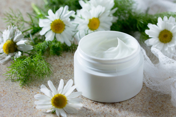 Face cream with chamomile on a brown stone background - beauty s - Foto, Imagen