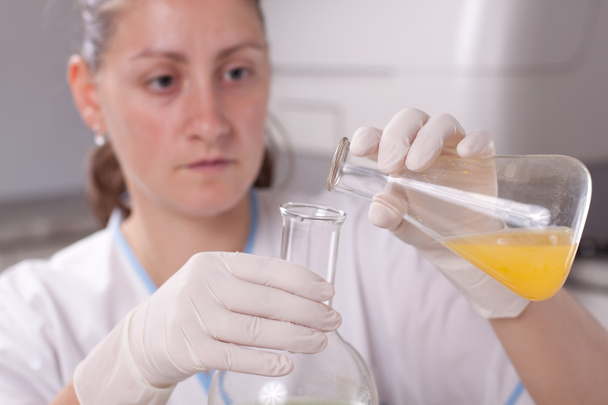 γυναίκα εξετάσει πολύχρωμα μπουκάλια γεμίζουν με χημικές ουσίες - Φωτογραφία, εικόνα