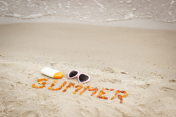 Inscription summer, sunglasses and sun lotion on sand at beach, sun protection, summer time - Fotoğraf, Görsel