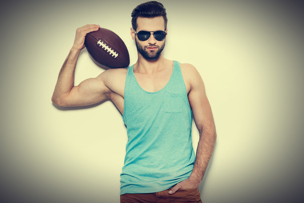 man in sunglasses carrying American football ball - 写真・画像