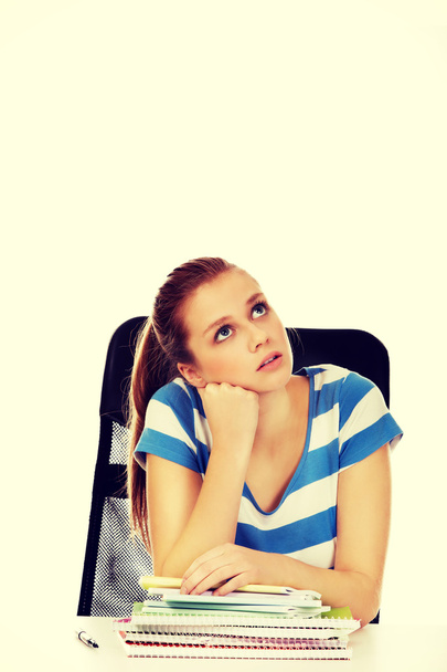 Teenage woman sitting behind the desk and thinking - Fotoğraf, Görsel
