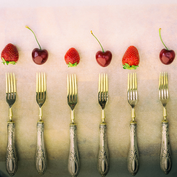 Vintage gekwadrateerde samenstelling met zilveren vorken aardbeien annd kersen - Foto, afbeelding