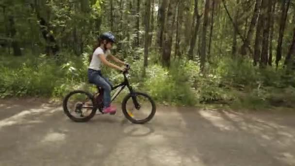 little girl rides her bike on a forest trail - Filmagem, Vídeo