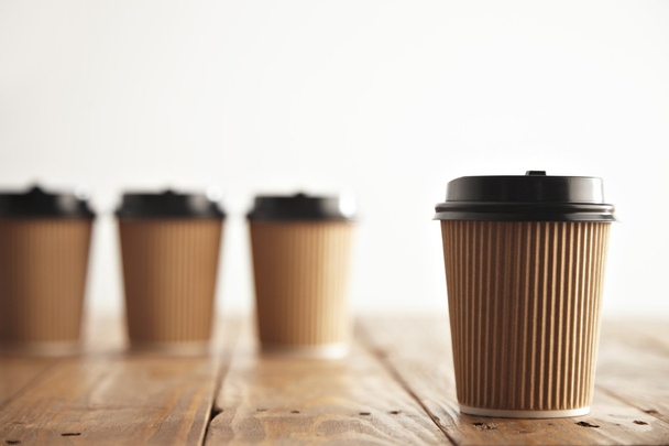 One focused paper coffee cup in front of unfocused others - 写真・画像