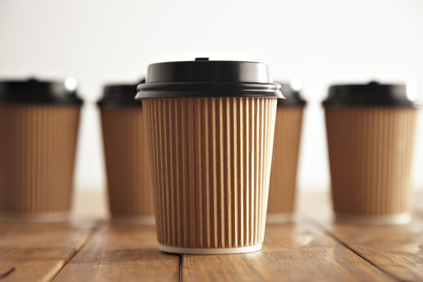 One focused paper coffee cup in front of unfocused others - 写真・画像