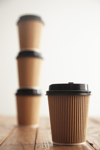 paper cup in front of three cups standing in column  - Photo, Image