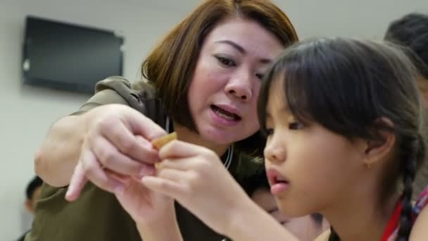 4K: bambino asiatico che impara a piegare origami di carta giapponese con insegnante, arte della piegatura della carta
. - Filmati, video