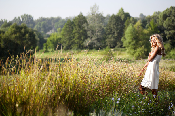 Girl in white dress walking on the meadow in summer day - Foto, Imagem