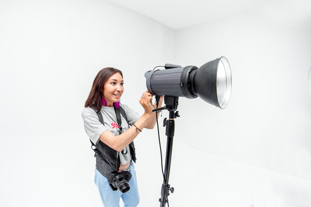 Fotógrafa mujer ajusta el equipo flash, cámara y softbox i
 - Foto, Imagen