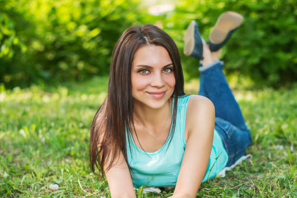 Beautiful woman relaxing outdoors on grass looking happy and smiling. - Foto, afbeelding