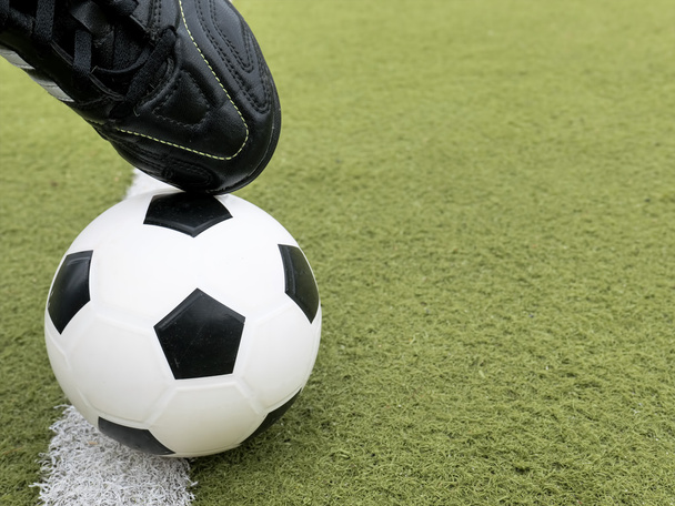 Balón de fútbol con pies de jugador en el campo de fútbol
. - Foto, imagen