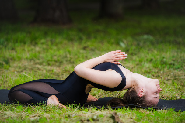 junge Frau beim Yoga, Rückenwirbelsäulenverdrehung liegend - Foto, Bild
