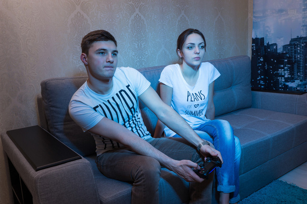 Nuori mies intohimoisesti peli istuu kotona hänen tyttöystävänsä
 - Valokuva, kuva