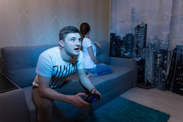 Здивований і розлючений чоловік захоплюється грою, сидячи вдома
 - Фото, зображення