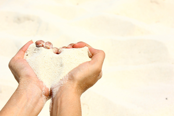 Closeup hands holding white sand heart shape - Fotó, kép