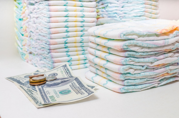 Pahalı çocuk bakımı. Çocuk bezi ve beyaz arka plan üzerinde para yığını - Fotoğraf, Görsel