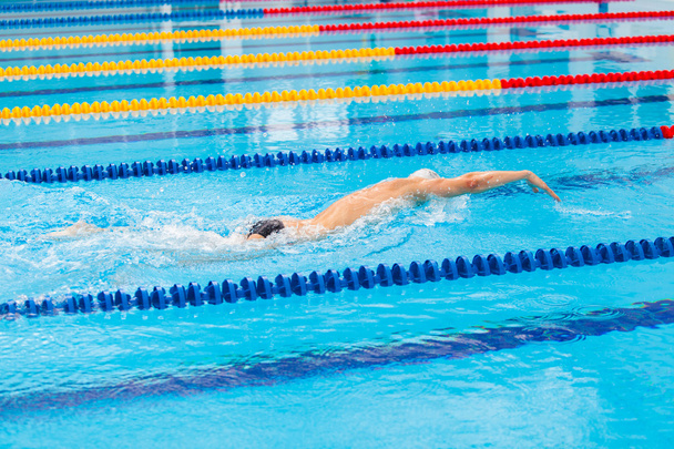 Man swimmer swimming crawl in blue water. - Zdjęcie, obraz