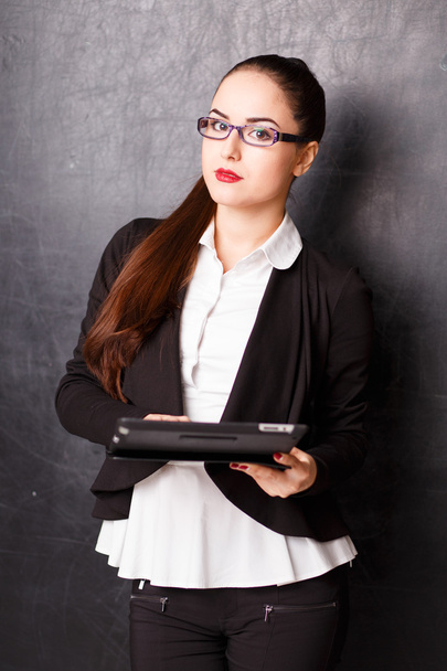 Portrait of young business lady in a jacket holding tablet computer over chalk board - Foto, Imagem