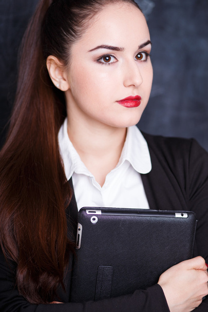 Portrait of young business lady in a jacket holding tablet computer over chalk board - Foto, afbeelding
